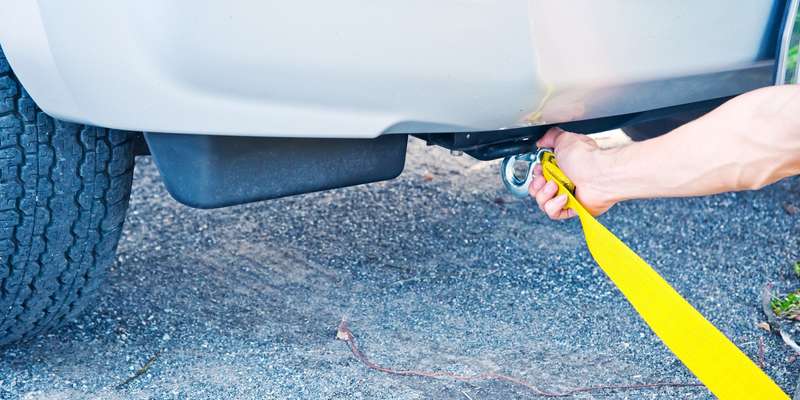 Hands towing car with towing rope