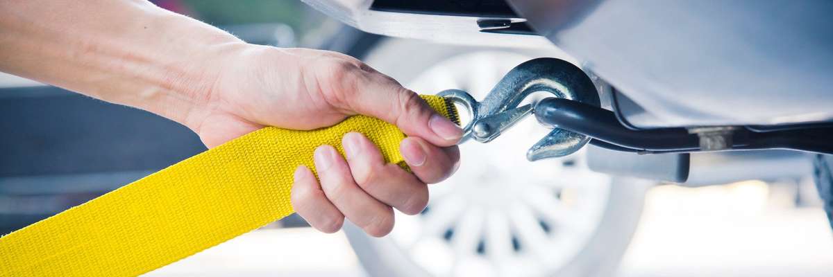 Hands towing car with towing rope