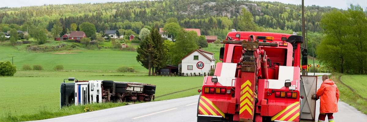 A red tow truck cleaning a rural town's highway