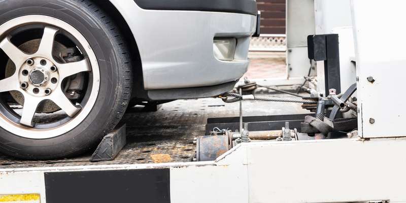 Broken down car towed onto flatbed tow truck